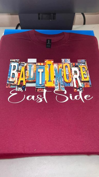 Maroon t-shirt featuring the text "BALTIMORE East Side" in colorful block letters.